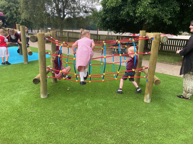 The outdoor play area has a number of interesting pieces of equipment for the children to play on, and the surroundings are bright an colourful, with blue coloured grass making zoned 'water' areas.
