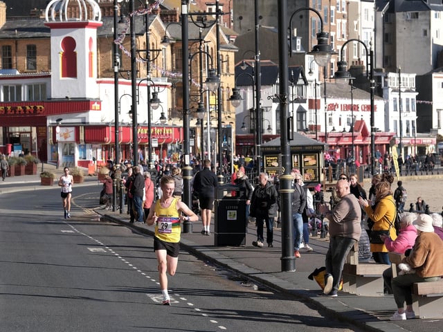 Scarborough Athletic Club's leading light Jackson Smith checks his watch as he nears the finish line at Scarborough 10k 2022, arriving in second place