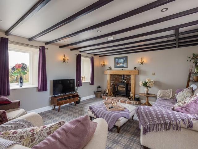 A beamed reception room with a cosy stove.