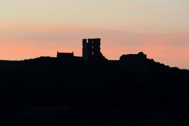 Castle silhouette against a pastel sunrise.