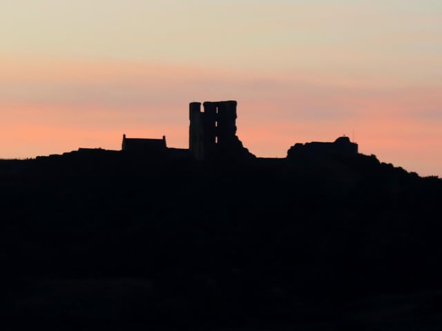 Castle silhouette against a pastel sunrise.
