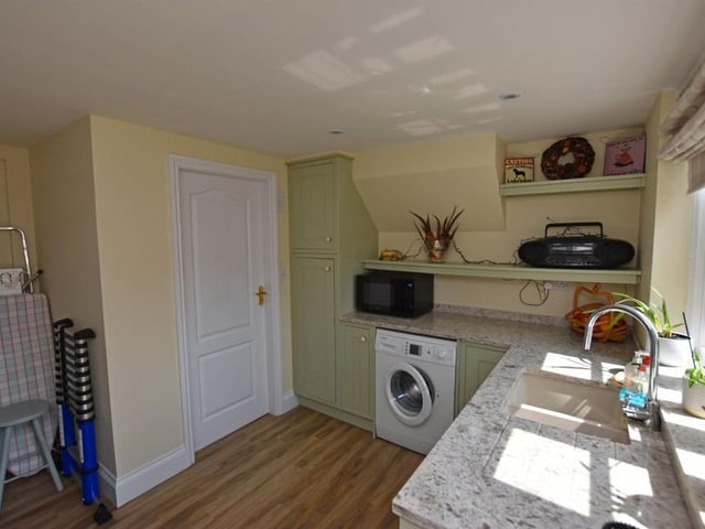The utility room has fitted units and shelving.