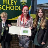 Michelle Lount, Charity Farm Caravan Park, presenting the 'Student of the Week' book to two Filey School students