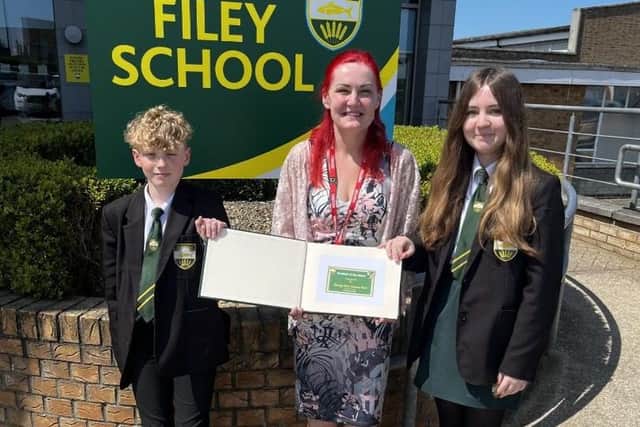 Michelle Lount, Charity Farm Caravan Park, presenting the 'Student of the Week' book to two Filey School students