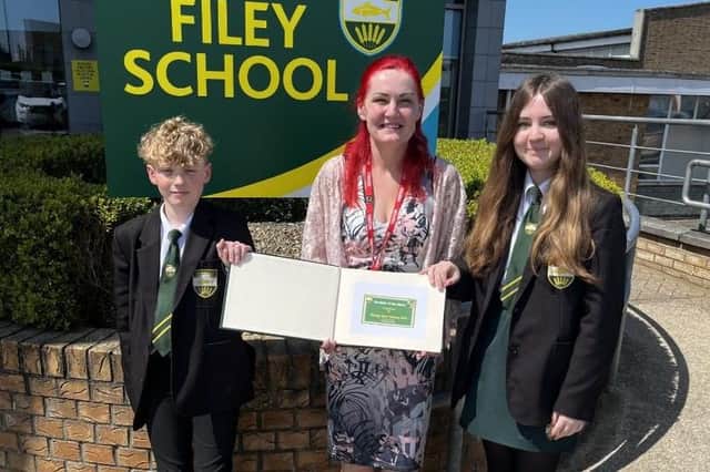 Michelle Lount, Charity Farm Caravan Park, presenting the 'Student of the Week' book to two Filey School students