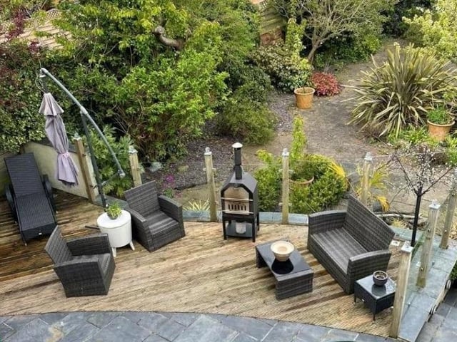 This home has a well-maintained garden with patio areas and decking, plus a garage, and driveway parking for multiple vehicles.