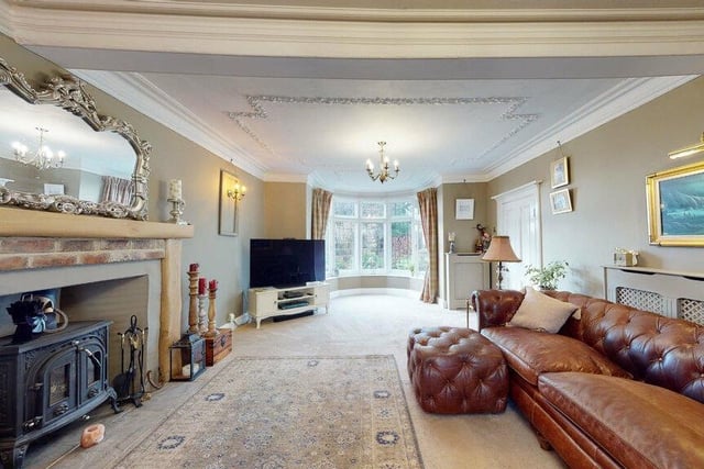 A comfortable lounge with bay window, feature fireplace with stove, and decorative detail to the ceiling.