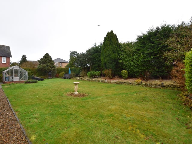 The rear lawned garden has mature leafy borders.