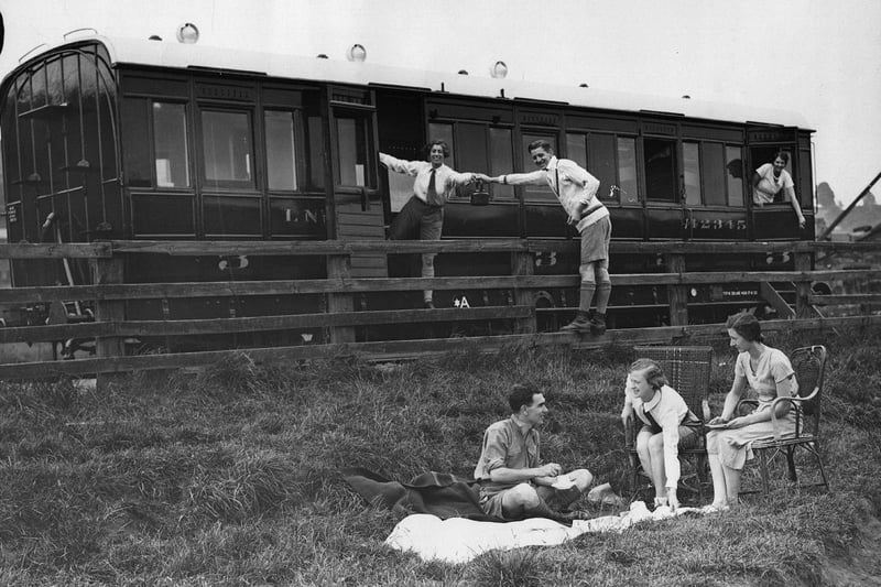 Campers preparing a meal alongside the railway carriage they are camping in, on the LNER camping site near Harrogate in June 1933.