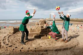 'Elves' have fun playing on Whitby beach by the Santa sand sculpture.