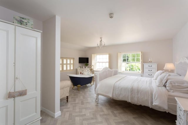 A large and bright bedroom with a free-standing, claw foot bath.