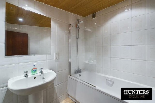 A fully tiled bathroom with white suite.