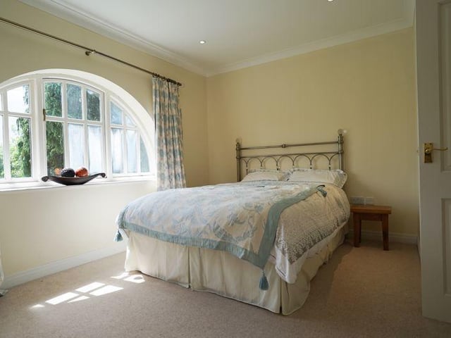 One of the double bedrooms within the house, with a feature arched window.