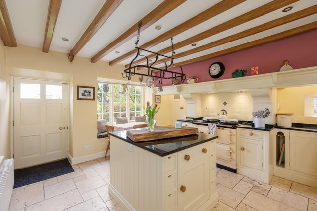 The bespoke farmhouse kitchen, with central island and window seat, also has an Aga.