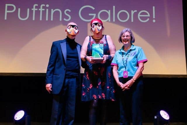 The Puffins Galore! team accepting their award while donning stunning puffin masks for the occasion.
