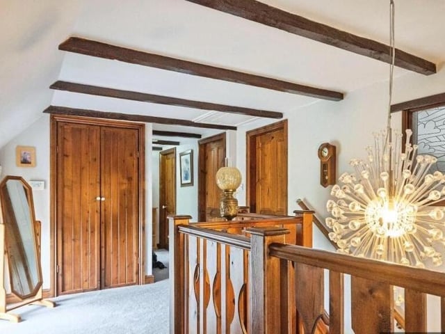 Wooden beams, bannister and doors on the first floor landing of the home.