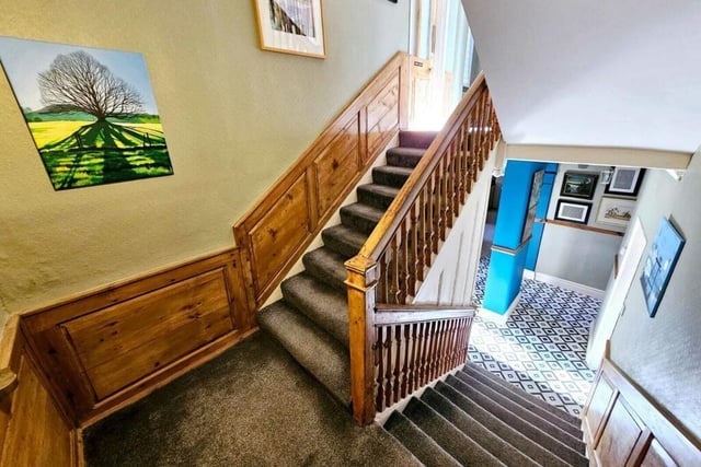 The wide, wooden panelled staircase leads to the upper floors from the hallway.