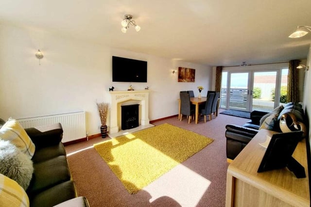The living room, with feature fireplace and doors leading outside.