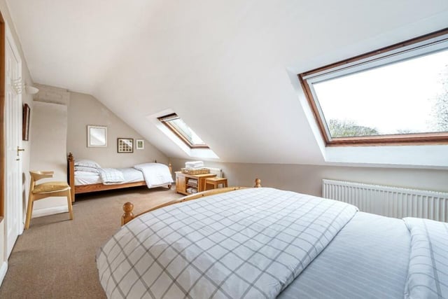 A long and light bedroom with velux windows.