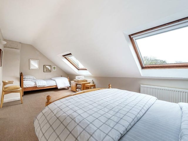 A long and light bedroom with velux windows.
