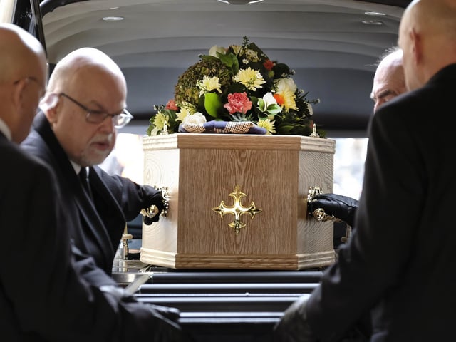 The coffin is removed from the hearse