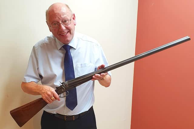 Auctioneer Graham Paddison with Lord Lilford's gun.