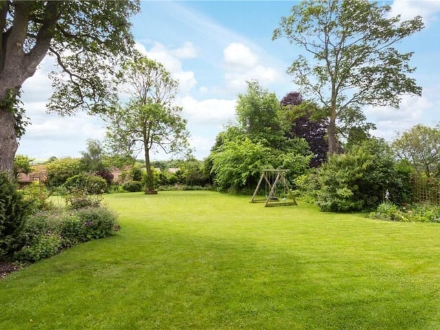 The lawned garden with mature trees and shrubs backs on to open countryside.