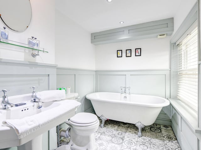 A stylish bathroom with wall panels and a free-standing, claw foot bath.