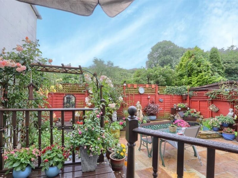 A colourful, enclosed garden framed by trees beyond.