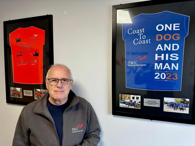Ken standing between the two t-shirts he wore for the charity walks