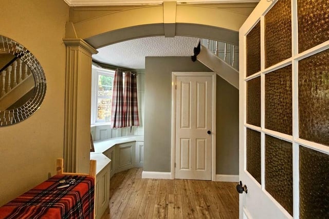 A section of the traditional style hallway, with a window seat and staircase up.