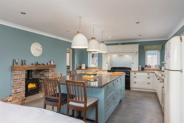 The bespoke, hand-made kitchen and diner with central island and rustic fireplace with stove.