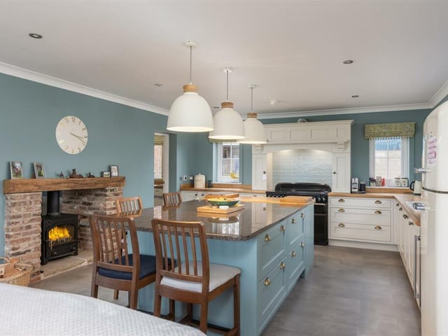 The bespoke, hand-made kitchen and diner with central island and rustic fireplace with stove.
