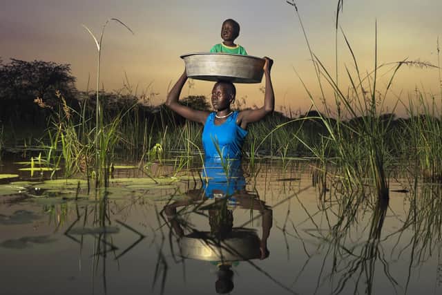 Nyarew Gatluak, 29, carefully carries her 2-year-old baby, Tito Beliu, through some of the worst floods the region has seen in 60 years.