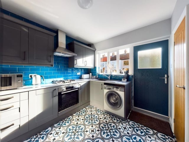 The kitchen has a range of fitted units with rolled top work surfaces, and an integrated oven and hob.