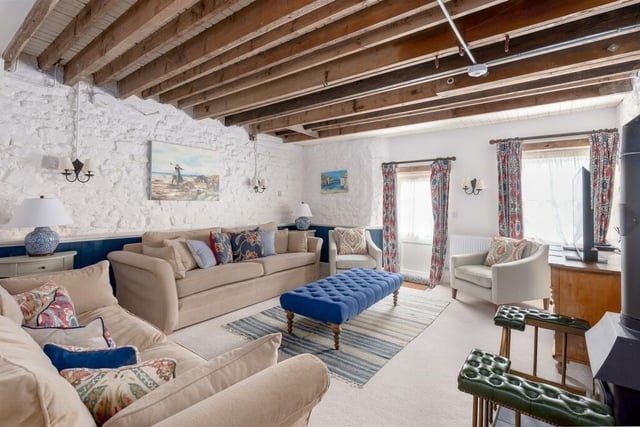 A large and light sitting room with exposed beams.