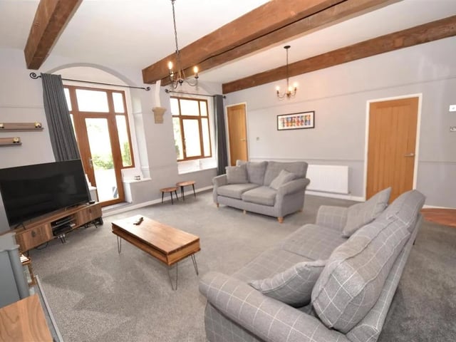A spacious living room with glass panel door and windows allowing light to flood in.
