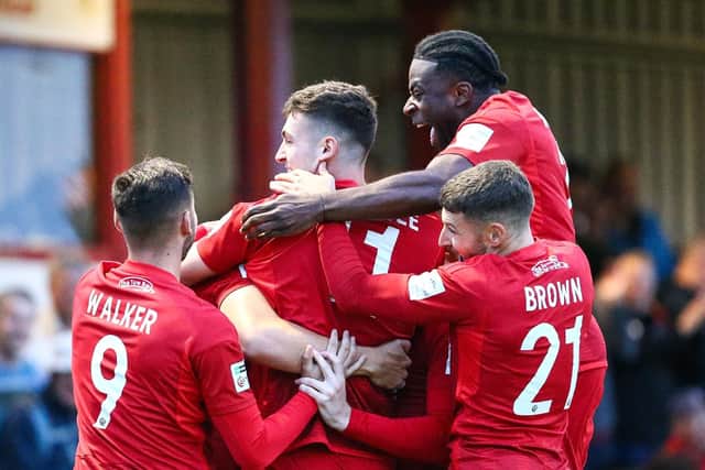 Team-mates swarm Jake Hull in celebration after he made it 2-0 v Buxton. Photo by Zach Forster