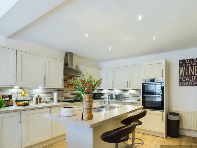 A pristine kitchen, with central island and breakfast bar.