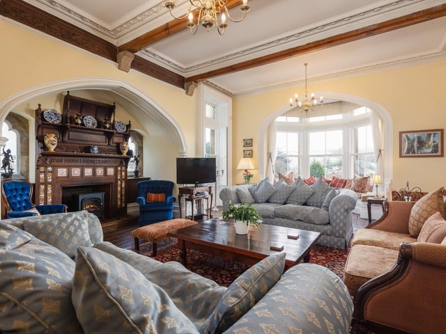 This Gothis drawing room features a fireplace with a large carved mahogany hood with carvings and decorative inset tiles/