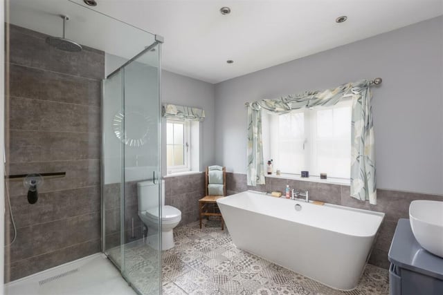 The modern bathroom is stylishly furnished with a free standing bath, a walk-in shower and wash basin with vanity unit.