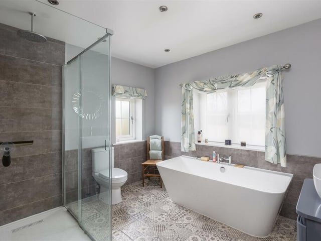 The modern bathroom is stylishly furnished with a free standing bath, a walk-in shower and wash basin with vanity unit.