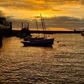 An orange sunrise above the harbour, by Ian Sandy.