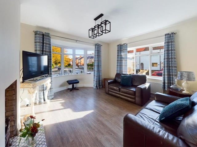 A bright and welcoming living room with a feature fireplace and a large bay window.