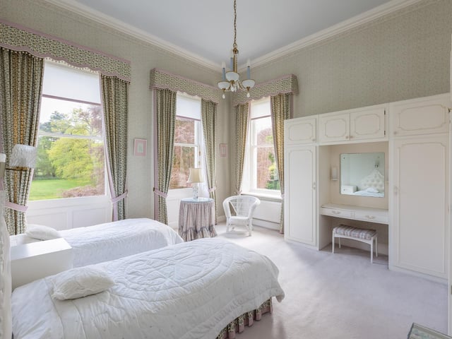 Another of the Hall's bedrooms, with built-in furniture, and lawned gardens with trees visible through the window.