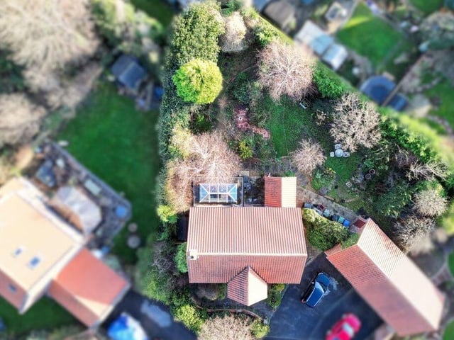 An aerial view of the home with its stunning gardens and triangular shape plot.