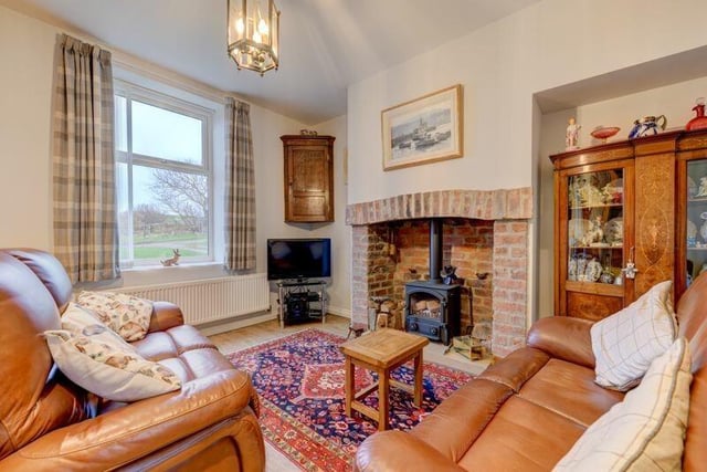A cosy lounge with rustic brick fireplace and stove has stunning views.