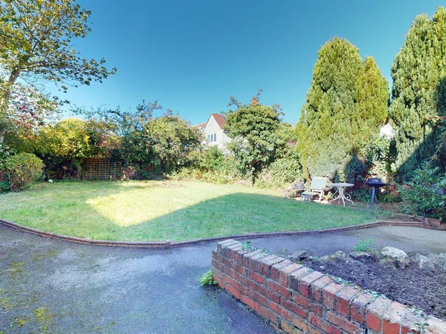 An area of lawned garden fringed with trees and bushes.