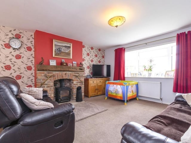 A spacious sitting room with central fireplace and stove.