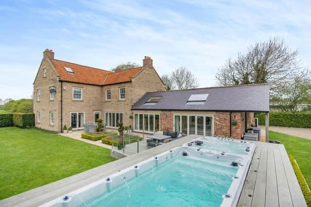 The luxurious village property's garden includes a swim spa with hot tub.